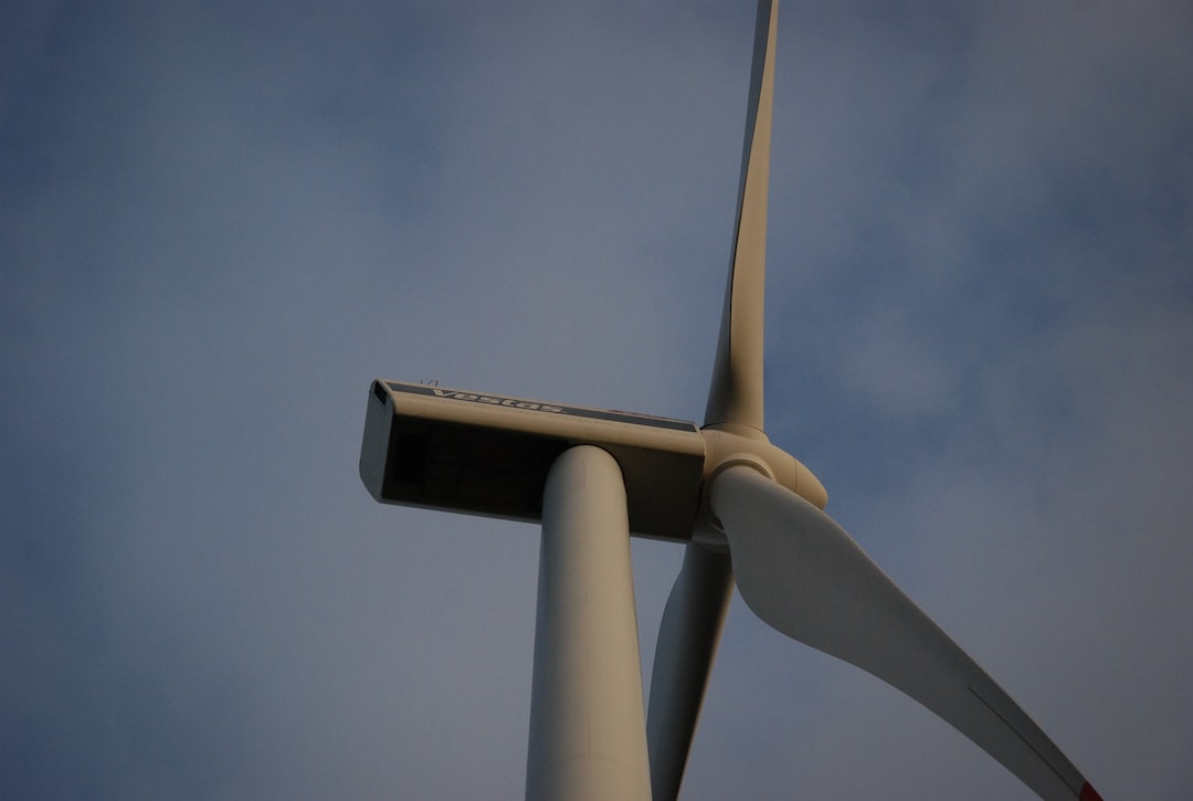 An image showcasing a vast landscape with multiple wind turbines in motion, their blades gracefully slicing through the air