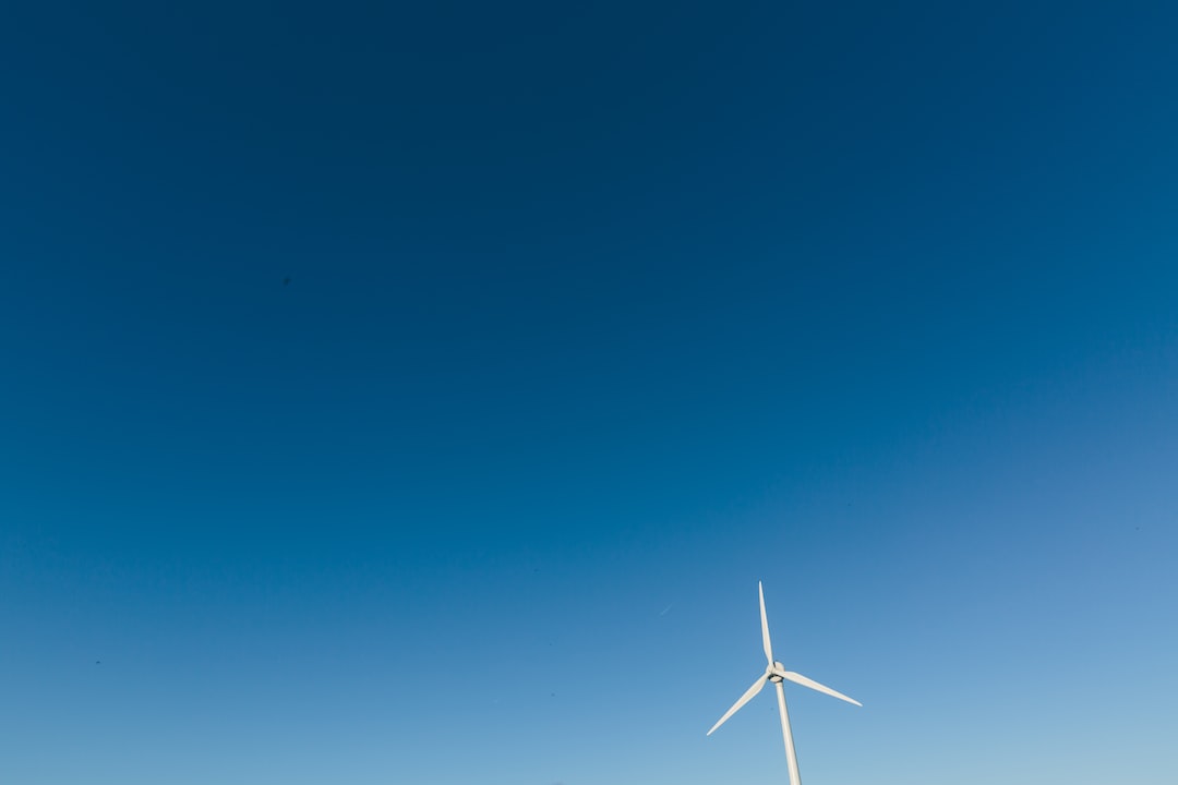 An image showcasing a vast landscape with a towering wind turbine at its center, emphasizing the immense length of its blade as it gracefully cuts through the air, capturing the essence of the average wind turbine blade length